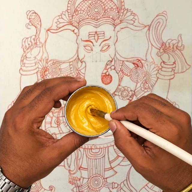 Mixing yellow paint in a bowl over the Ganesha line drawing