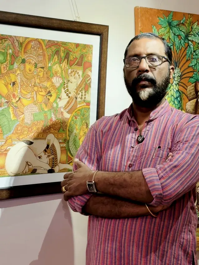 Dr. Saju Thuruthil beside one of his Kerala mural paintings